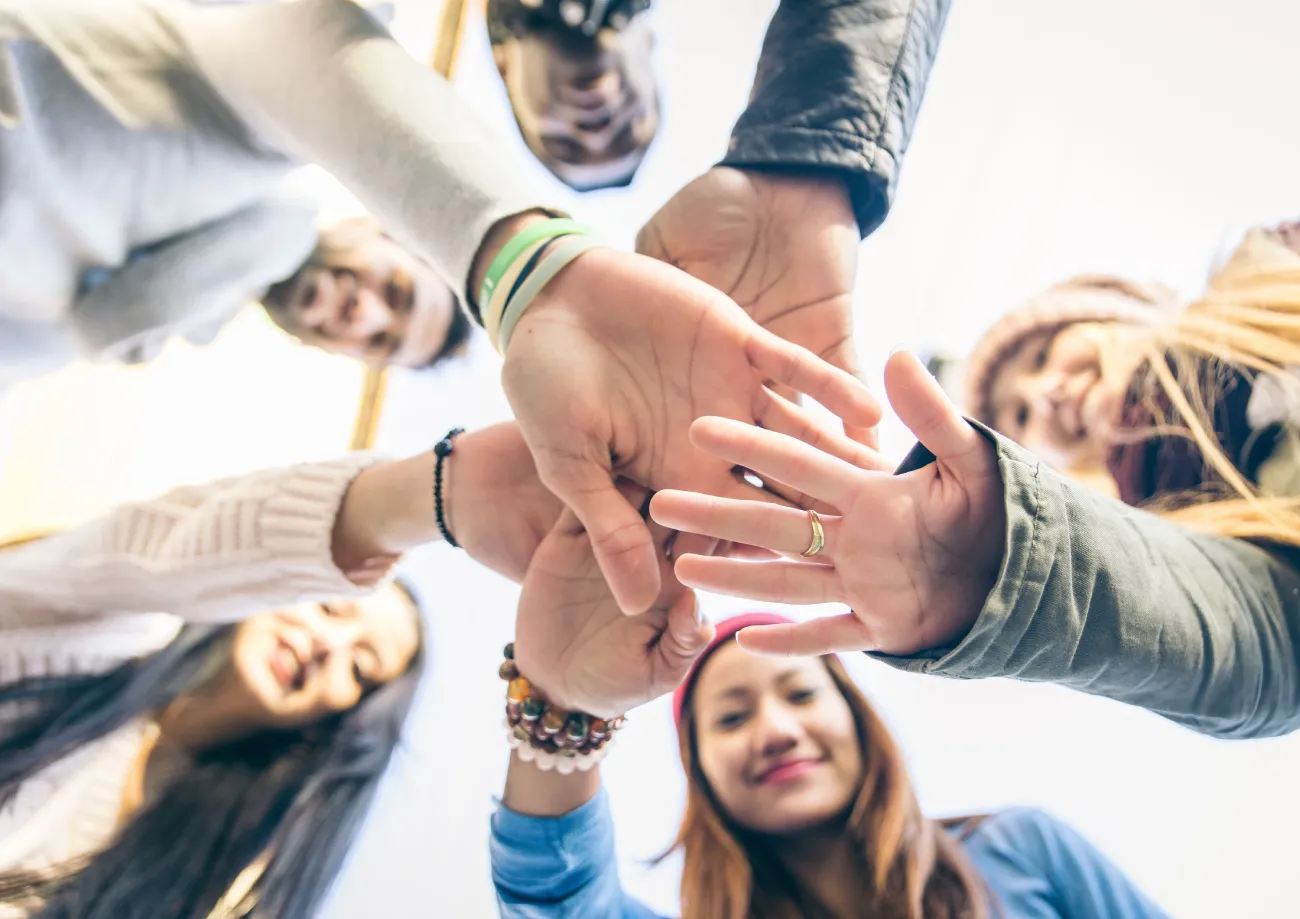 Photo d'accompagnement qui représente des personnes qui posent leur main les unes sur les autres